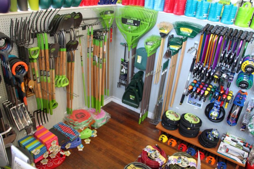 Shoe shelves display product under hanging tools at Garden Fever